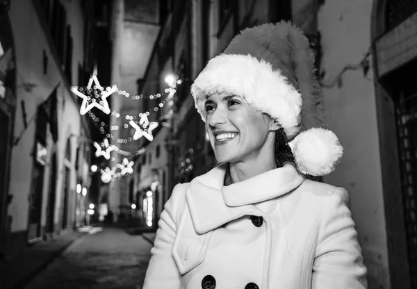 Gezi Floransa'da Noel anda ilham dolu. mesafe içine bakarak gülümseyen genç kadın Noel şapkalı Floransa, İtalya