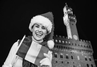 Gezi Floransa'da Noel anda ilham dolu. Gülümseyen İtalyan bayrağı ile Floransa, İtalya Palazzo Vecchio önünde Noel şapkalı modern turist kadın portresi