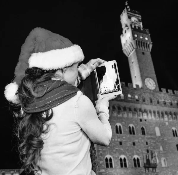 Gezi Floransa'da Noel anda ilham dolu. Floransa, İtalya alarak fotoğraf tablet Pc ile Noel şapka Palazzo Vecchio karşı genç turist kadının arkasından gördüm