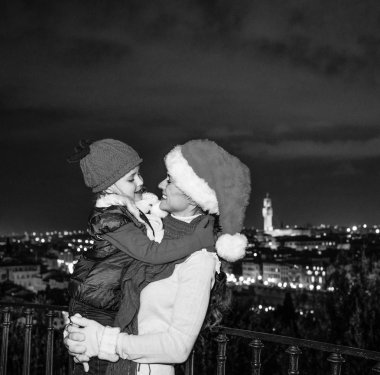 Gezi Floransa'da Noel anda ilham dolu. Modern anne ve çocuk gezginler ile Noel şapka Piazzale Michelangelo, Floransa, İtalya kucaklayan içinde gülümseyen