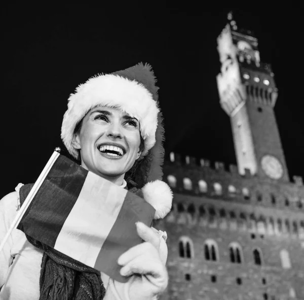 Gezi Floransa'da Noel anda ilham dolu. Palazzo Vecchio Floransa, İtalya karşı Noel şapkasıyla İtalyan bayrağı mesafe içine bakarak mutlu modern turist kadın portresi