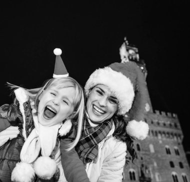 Gezi Floransa'da Noel anda ilham dolu. Neşeli Genç Anne ve kızı gezginler Floransa, İtalya Palazzo Vecchio karşı Noel şapka ile portre
