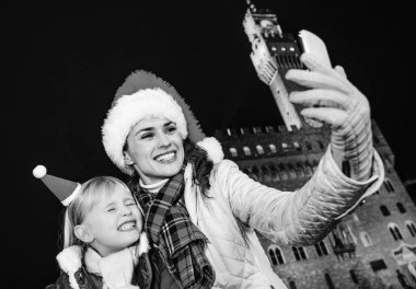 Gezi Floransa'da Noel anda ilham dolu. mutlu genç anne ve kızı turist Palazzo Vecchio önünde Noel şapkalı Floransa, İtalya alarak selfie telefon ile