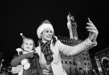 Gezi Floransa'da Noel anda ilham dolu. Modern anne ve çocuk turist Palazzo Vecchio önünde Noel şapkalı Floransa, İtalya alarak selfie telefon ile gülümseyen portresi