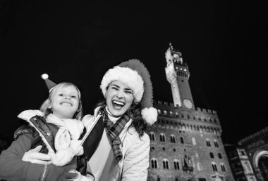 Gezi Floransa'da Noel anda ilham dolu. Mutlu modern anne ve kızı gezginler bayrak ile Noel şapka Floransa, İtalya ile portre