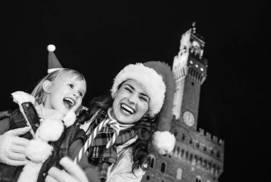 Gezi Floransa'da Noel anda ilham dolu. Genç Anne ve çocuk turist Noel şapka Palazzo Vecchio Floransa, İtalya Noel şeker kamışı gösterilen karşı gülümseyen portresi