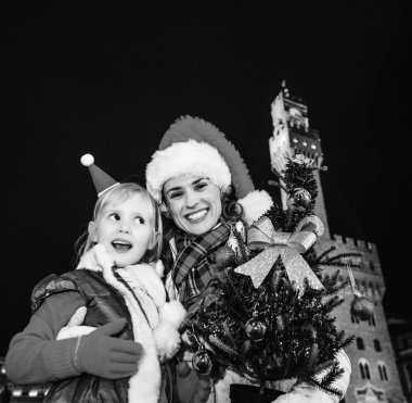 Gezi Floransa'da Noel anda ilham dolu. Mutlu genç anne ve kızı turist Floransa, İtalya Noel şapka Noel ağacı ile portre
