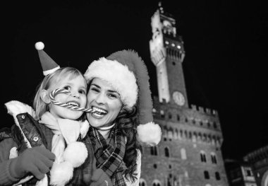 Gezi Floransa'da Noel anda ilham dolu. Noel şekeri yiyen mutlu genç anne ve çocuk gezginler ile Noel şapka Palazzo Vecchio karşı Floransa, İtalya portresi