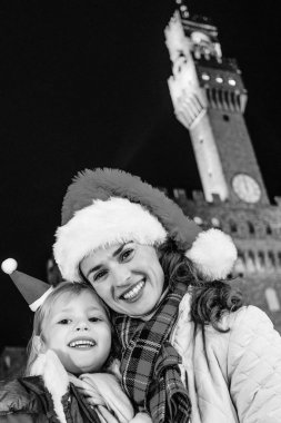 Gezi Floransa'da Noel anda ilham dolu. mutlu genç anne ve kızı turist Noel şapka önünde Palazzo Vecchio, Florence, İtalya