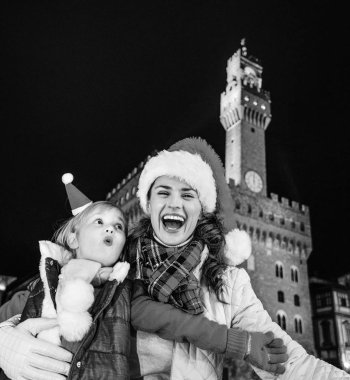 Gezi Floransa'da Noel anda ilham dolu. Genç Anne ve kızı turist Noel şapka Palazzo Vecchio Floransa, İtalya eğleniyor karşı gülümseyen portresi zaman