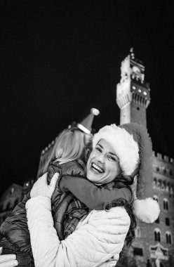 Gezi Floransa'da Noel anda ilham dolu. Genç Anne ve kızı turist Noel şapka önünde Palazzo Vecchio, Florence, İtalya kucaklayan gülümseyen portresi