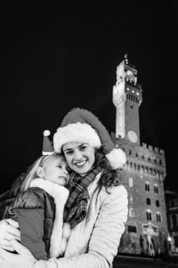Gezi Floransa'da Noel anda ilham dolu. Mutlu genç anne ve çocuk gezginler ile Noel şapka karşı Palazzo Vecchio, Florence, İtalya kucaklayan portresi