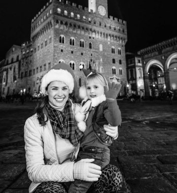 Gezi Floransa'da Noel anda ilham dolu. Genç Anne ve kızı gezginler Palazzo Vecchio önünde Noel şapkalı Floransa, İtalya handwaving ile gülümseyen portresi