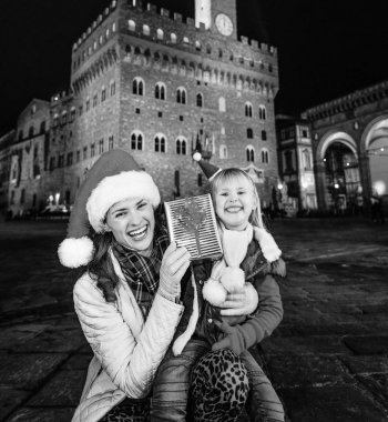 Gezi Floransa'da Noel anda ilham dolu. Genç Anne ve kızı turist Noel şapka Floransa, İtalya gösteren Noel mevcut kutusunda gülümseyen portresi