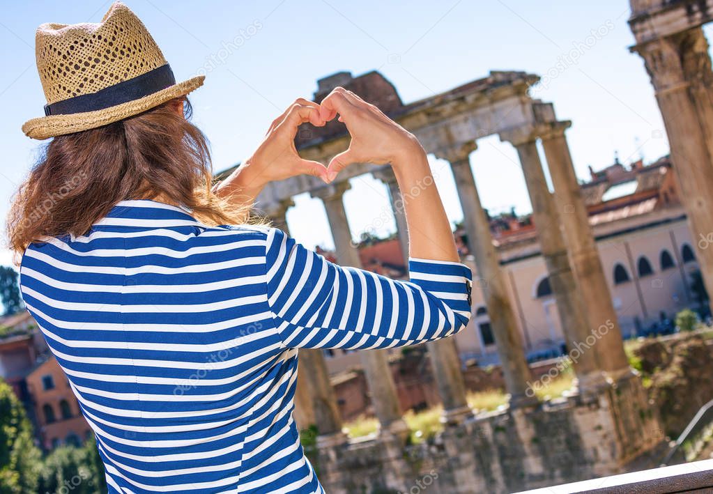 Roman Holiday. Seen from behind trendy tourist woman in Rome, Italy showing heart shaped hands