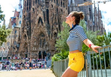 Barcelona - 10 Temmuz 2017: Portre rahat şık turist kadının sarı şort ve Barcelona, İspanya Sagrada Familia yakınındaki çizgili gömlek