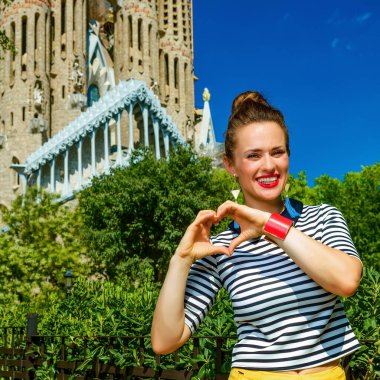 Barcelona - 10 Temmuz 2017: modern turist kadın sarı şort ve Barcelona, İspanya kalp gösterilen çizgili gömlek el şeklinde
