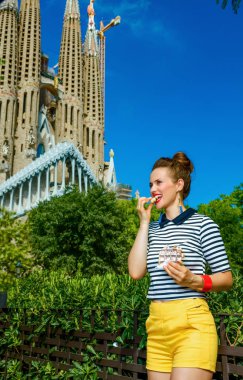 Barcelona - 10 Temmuz 2017: şık kadın sarı şort ve Sagrada Familia için Barselona, İspanya, gözleme yemek yakınındaki çizgili gömlek