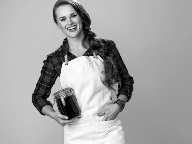 mutlu genç kadın çiftçi kavanoz bal ile önlük giyiyor