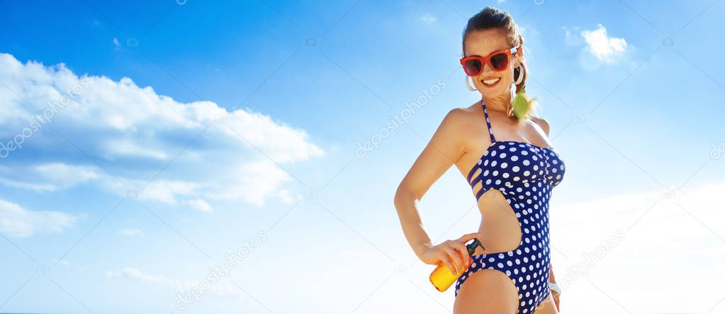  happy active woman in beachwear on the beach applying suntan lotion
