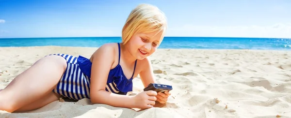 Sun kissed beauty. smiling blond girl in swimwear on the seashore viewing photos on camera