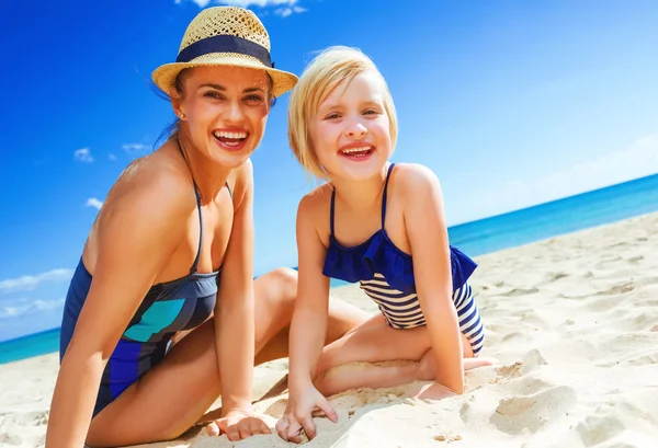 太陽に輝く美しさ 海岸で水着で笑顔の若い母と娘 — ストック写真
