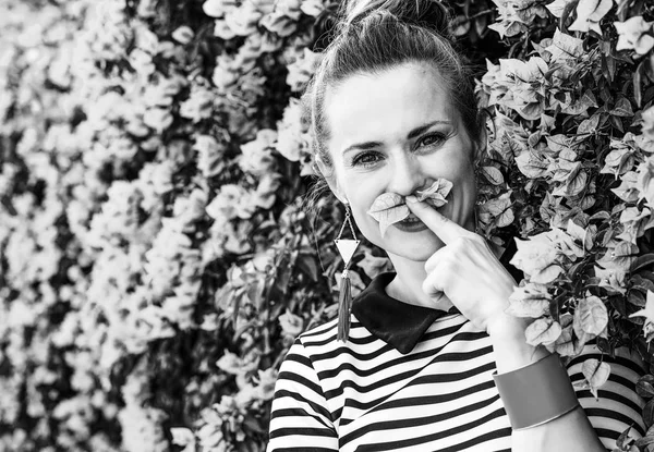 ショート パンツと花の前のストライプ シャツでリラックスした若い女性の肖像画 — ストック写真