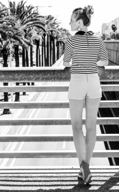 Nosing çevresinde, eğleniyor. Trendy kadın şort ve Otoban şehrin mesafe içine bakarak karşı çizgili gömlek gülümseyen