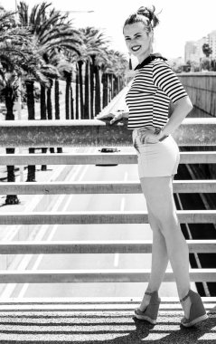 Nosing çevresinde, eğleniyor. Trendy kadın şort ve Otoban şehrin mesafe içine bakarak karşı çizgili gömlek gülümseyen