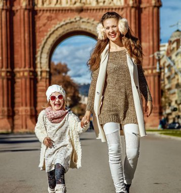 Son moda anne ve kızı Arc de Triomf yakınındaki Barselona, İspanya, yürüme gülümseyen tam uzunlukta portresi