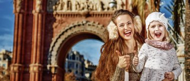 Son moda anne ve çocuk Arc de Triomf Barcelona, İspanya yakınındaki başparmak gösteren harita ile gülümseyen portresi