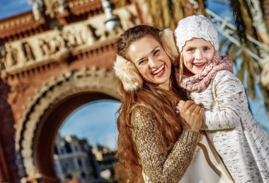 gülümseyen trendy anne ve çocuğun yanında Arc de Triomf, Barselona, İspanya, sarılma