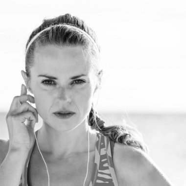 Vahşi deniz tarafı egzersiz yenileniyor. Portre sağlıklı fitness kadının spor müzik kulaklık ile sahil üzerinde dişli