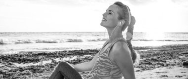 Vahşi deniz tarafı egzersiz yenileniyor. deniz kıyısı üzerinde oturan spor giyim rahat sağlıklı aktif kadında