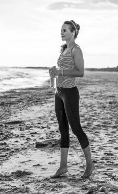 Vahşi deniz tarafı egzersiz yenileniyor. Sahilde mesafe içine bakarak ve egzersiz yaptıktan sonra rahatlatıcı spor giysili genç fitness kadın portresi tam uzunlukta