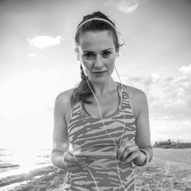 Vahşi deniz tarafı egzersiz yenileniyor. spor vites müzik kulaklık ile sahilde etkin sağlıklı kadın