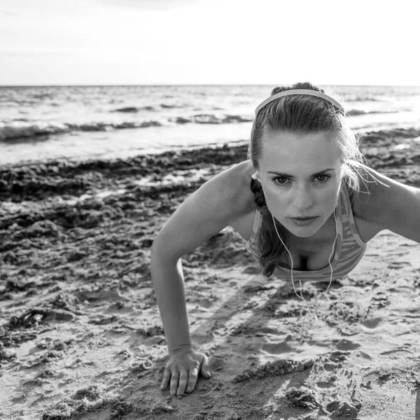 Refreshing wild sea side workout. active fitness woman in sportswear on the beach doing pushups