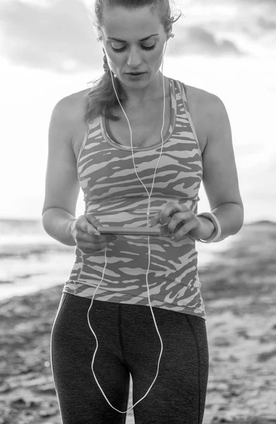 Refreshing wild sea side workout. healthy fitness woman in sports gear on the seashore with headphones listening to the music