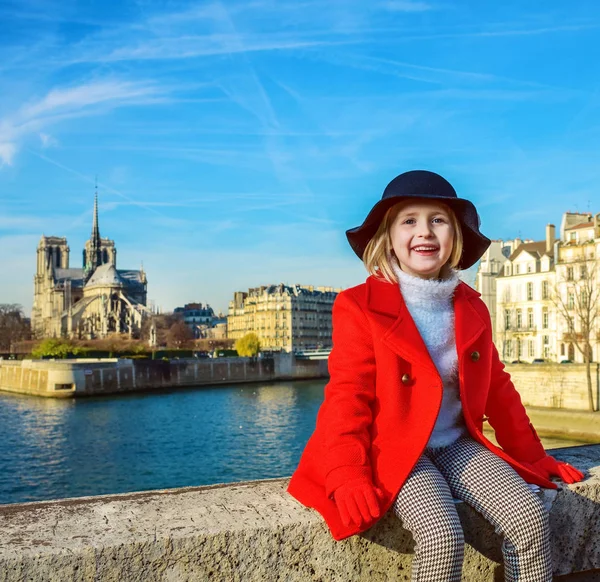パリで明るい リラックスしたパリ フランスで堤防に赤いコートで幸せな近代的な子供の肖像画 — ストック写真