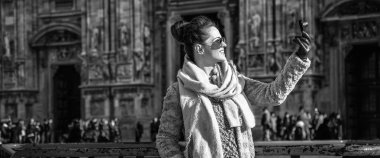 mutlu genç kadın kürk manto ve Duomo Milan, İtalya önünde güneş gözlüğü ile dijital fotoğraf makinesi alarak fotoğraf