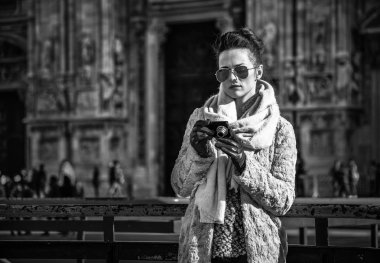 Trendy seyahat kadın kürk manto ve güneş gözlüğü önünde fotoğraf kamera görüntüleme Katedrali, Milano, İtalya