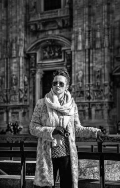 Genç gezgin kadın kürk manto ve güneş gözlüğü önünde mesafe içine dijital fotoğraf makinesi tutarken seyir Duomo Milan, İtalya