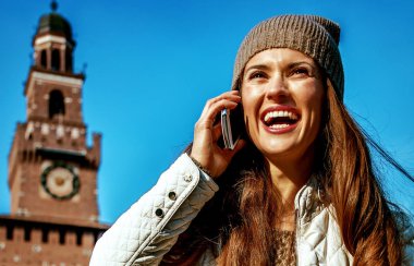 gülümseyen bir cep telefonuyla konuşan trendy seyahat kadın yakınındaki Sforza Kalesi, Milano, İtalya