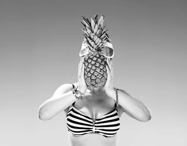 完美的夏天 穿泳装的年轻妇女在海岸举行菠萝在面孔前面 — 图库照片