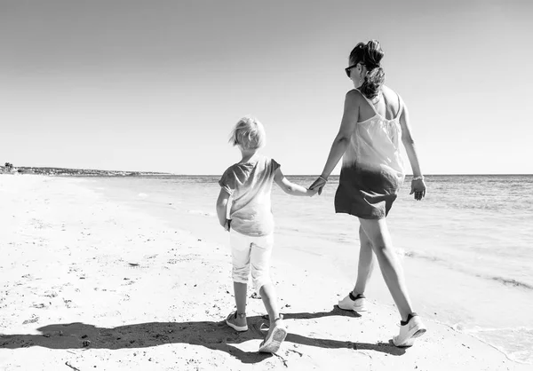 歩いて海岸にカラフルな服でモダンな母と娘の完全な長さの肖像画 — ストック写真