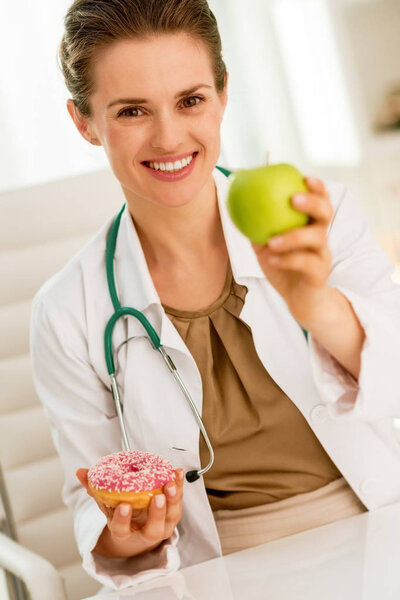 Счастливая женщина врач дарит яблоко вместо пончика
