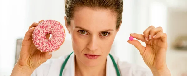 严重的内科医生女人表现出甜甜圈和丸 — 图库照片