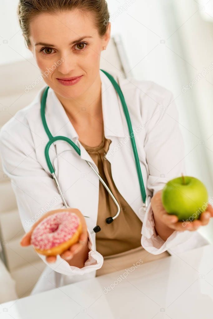 Medical doctor woman giving a choice between apple and donut