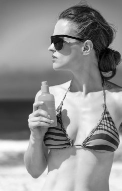 Mavi deniz, beyaz kum cenneti. Güneş gözlüğü ve bikini sahil ile güneş kremi sürmek üstünde genç kadın portresi