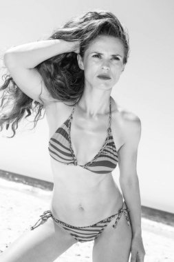 Mavi deniz, beyaz kum cenneti. beachwear mesafe içine arayan sahil üzerinde uzun esmer saçlı modern kadın